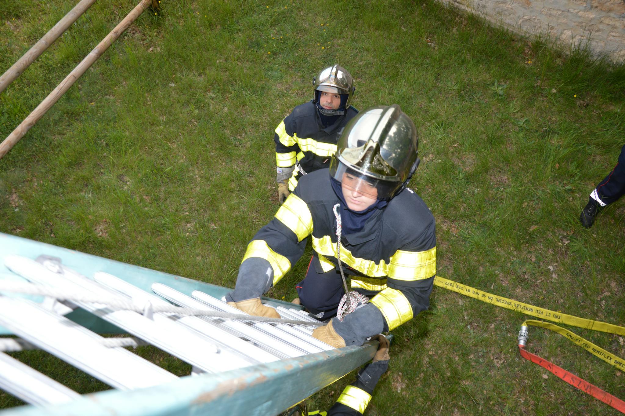A firefighter climbs a ladder during a training exercise, with safety gear and protective clothing.